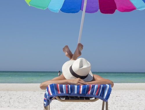 A lady simply sunbathing on a beach lounger by the beach on a striped towel