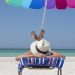 A lady simply sunbathing on a beach lounger by the beach on a striped towel