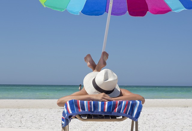 A lady simply sunbathing on a beach lounger by the beach on a striped towel